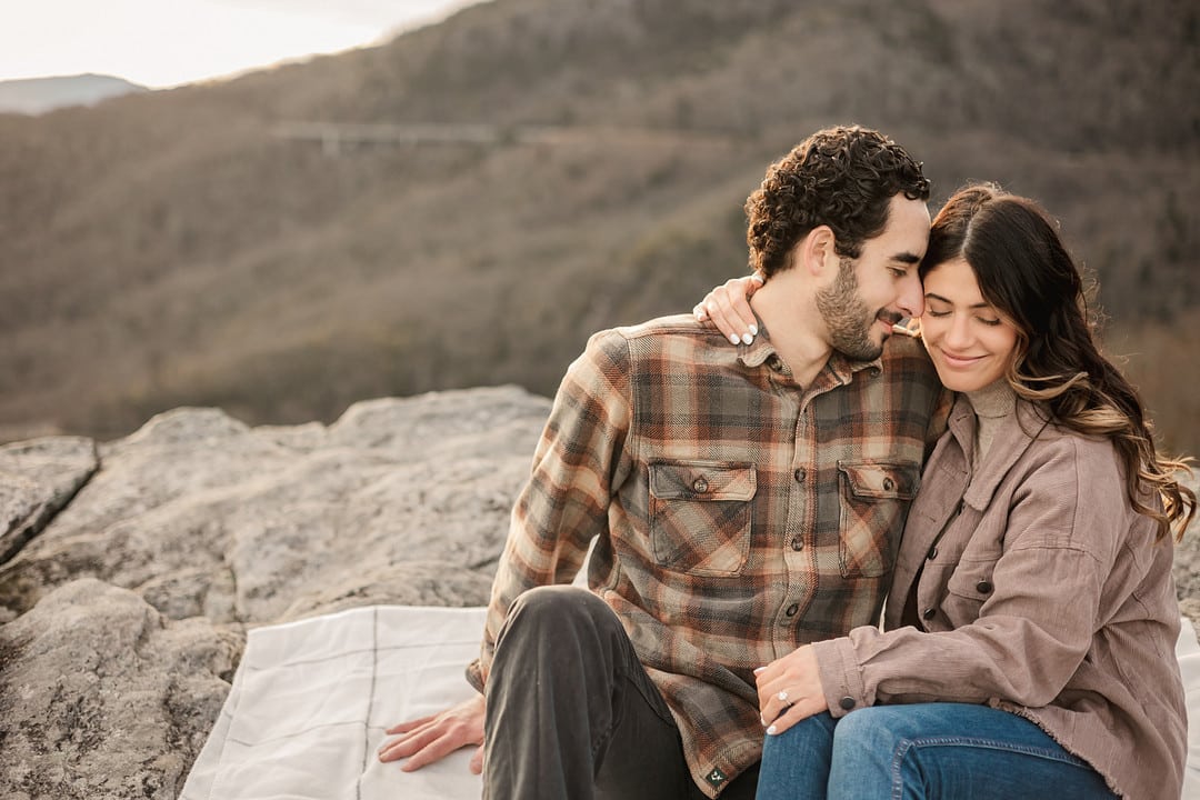 Engagement photograph of couple sitting on a rock