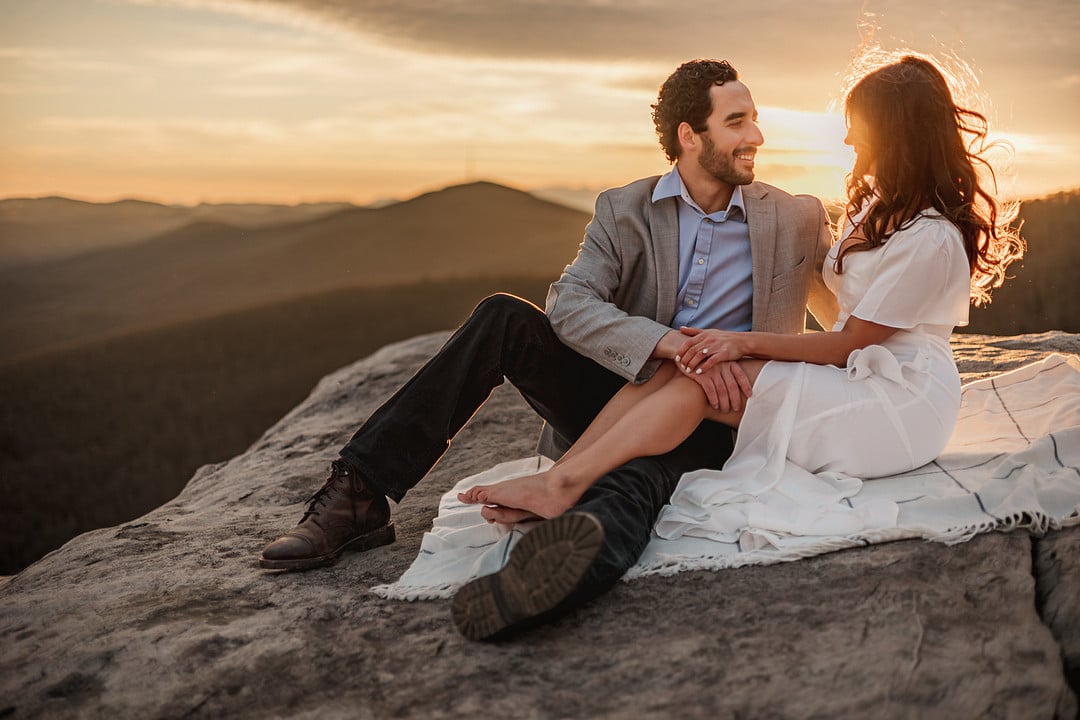 Wedding photograph of couple sitting on a rock at sunset