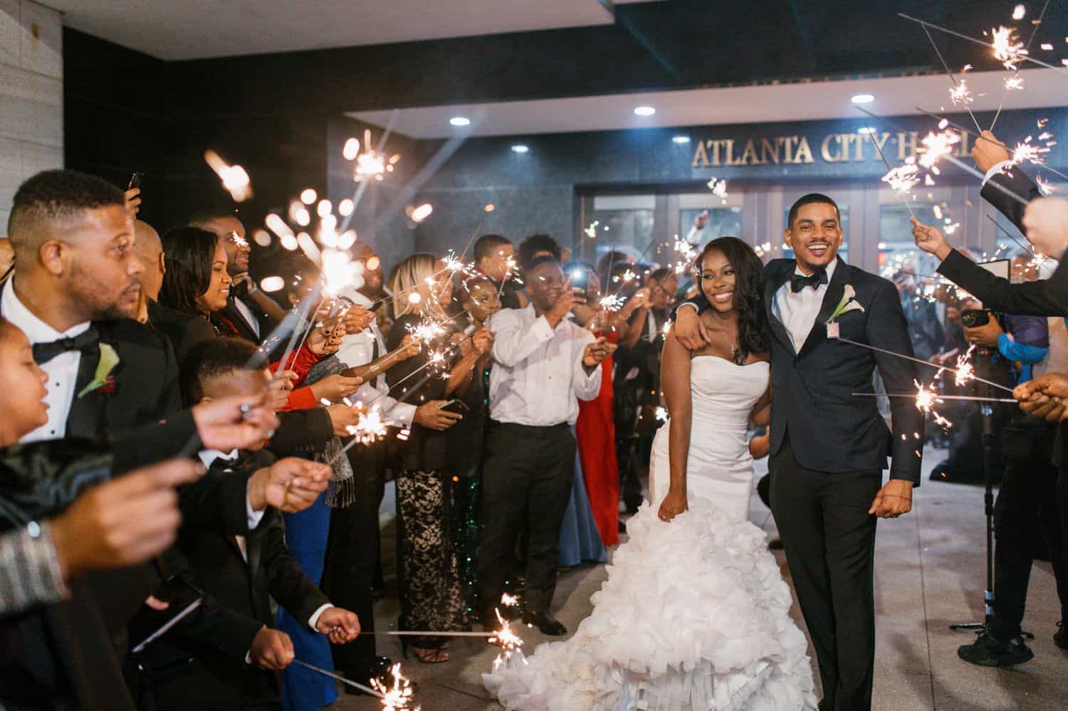 A couple runs through a tunnel of sparklers held by guests at the end of their wedding