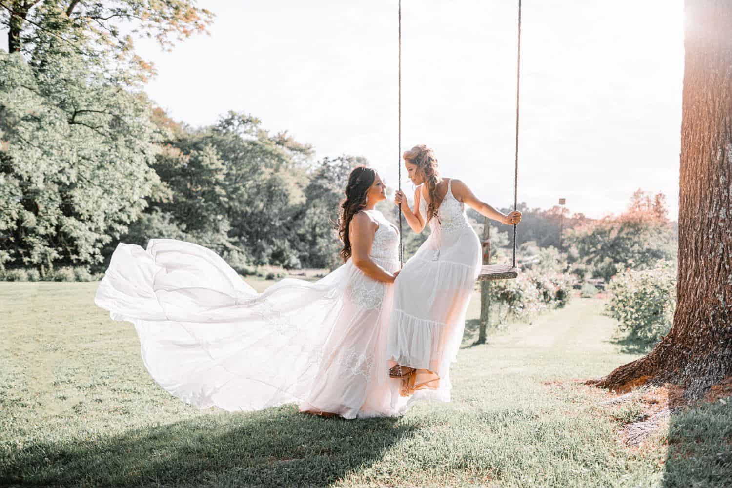An outdoor wedding portrait of two brides on a swing