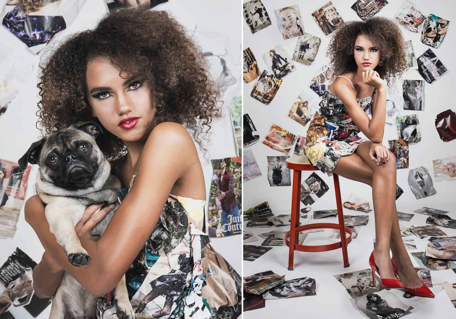 A Black model holding a pug dog poses on a red stool against a white wall plastered with photographs