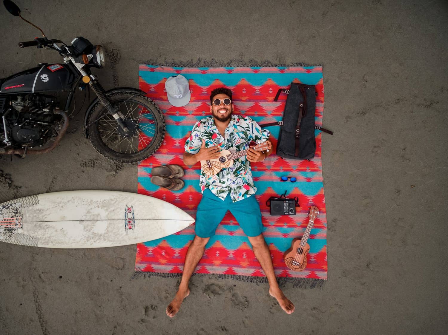 A man playing ukulele while lying on the beach