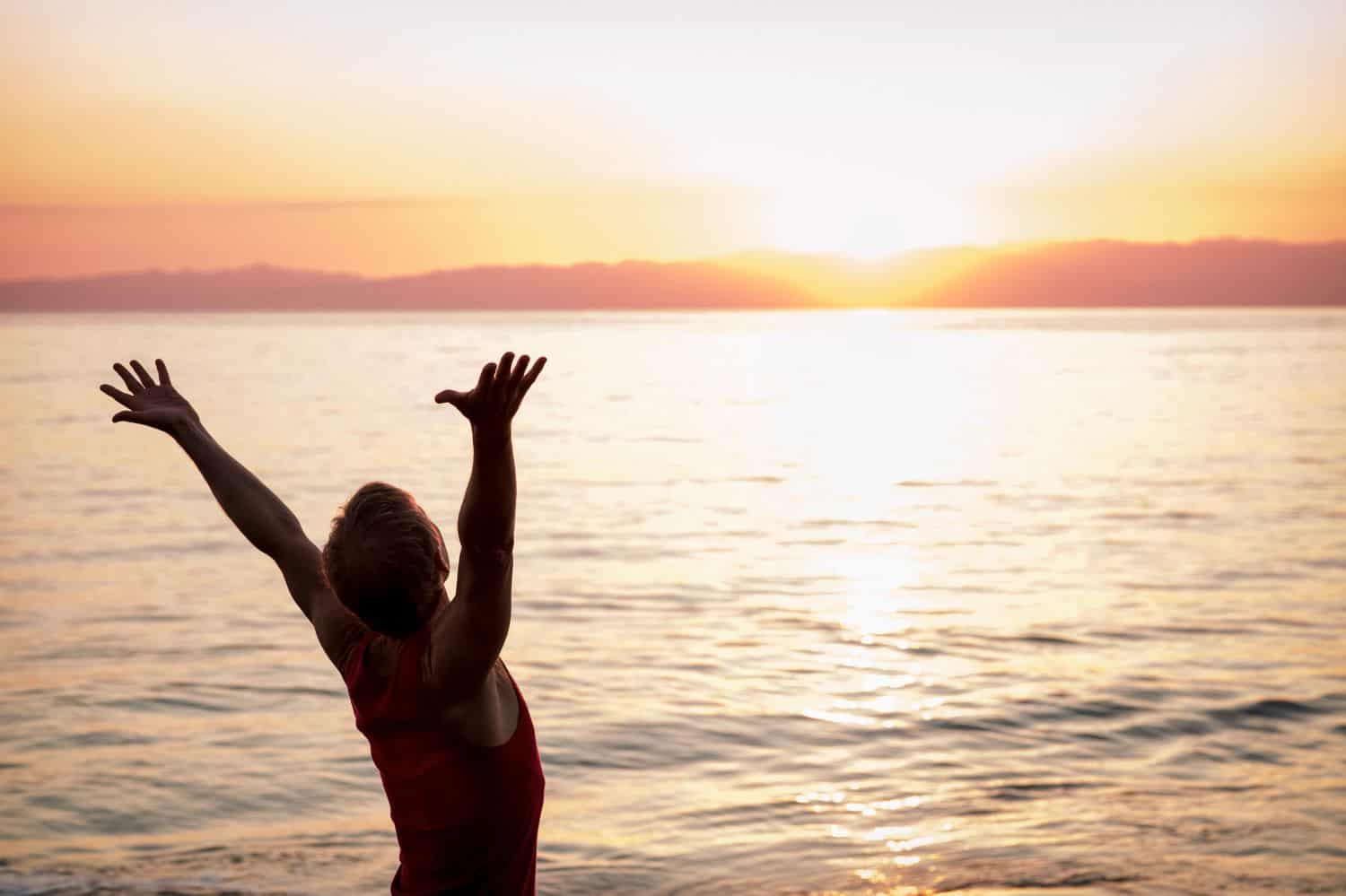 A man stretching his arms in front of the sea