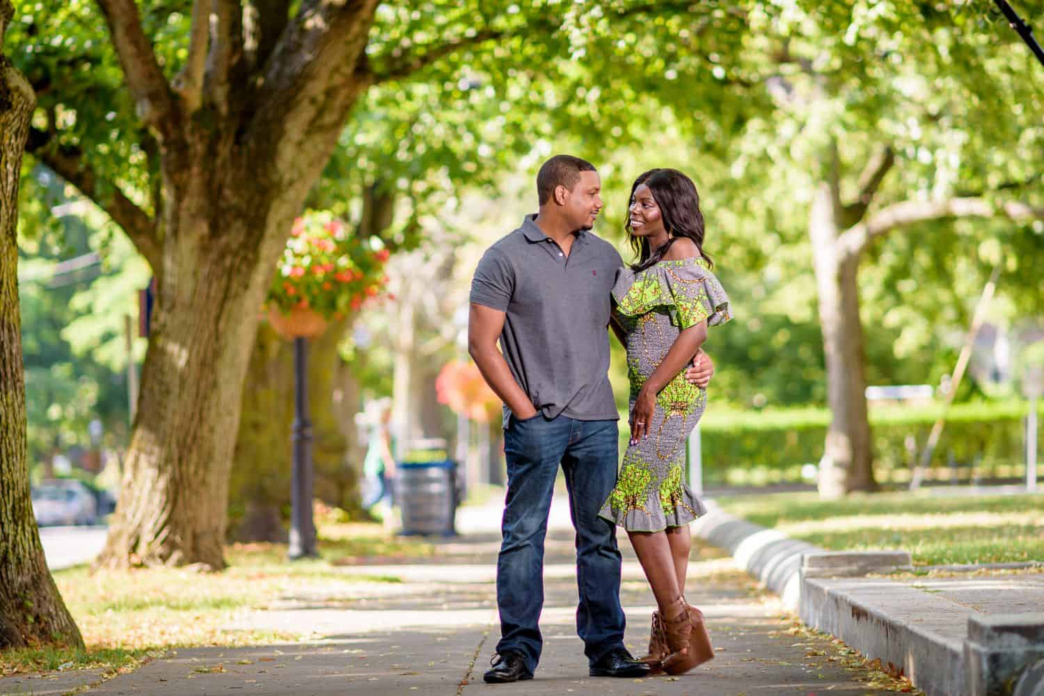 A couple snuggles close while standing in a sunlit street