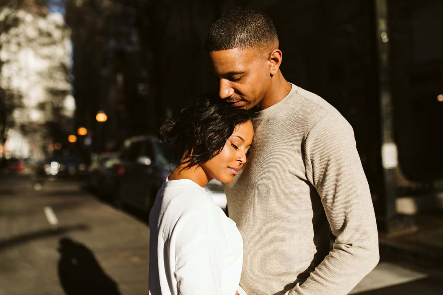 A Black couple enjoys the warm sun shining in a city street outside their Atlanta Airbnb
