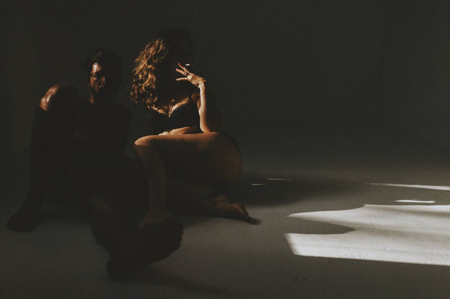 Photo: Christina Karst's moody couple's boudoir portrait shows only an outline of a couple reclining on a white floor as the woman smokes a cigarette.