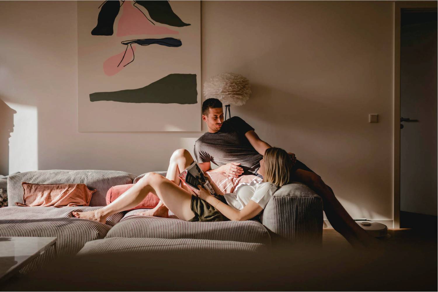 Photo: Diana Frohmueller's in-home lifestyle portrait of a couple depicts them reclining on a large gray sofa. An abstract painting hands on the wall behind them.