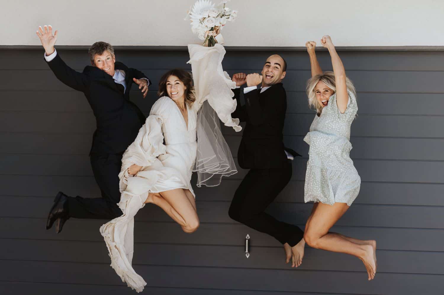 Family members jump in the air for a silly wedding day portrait