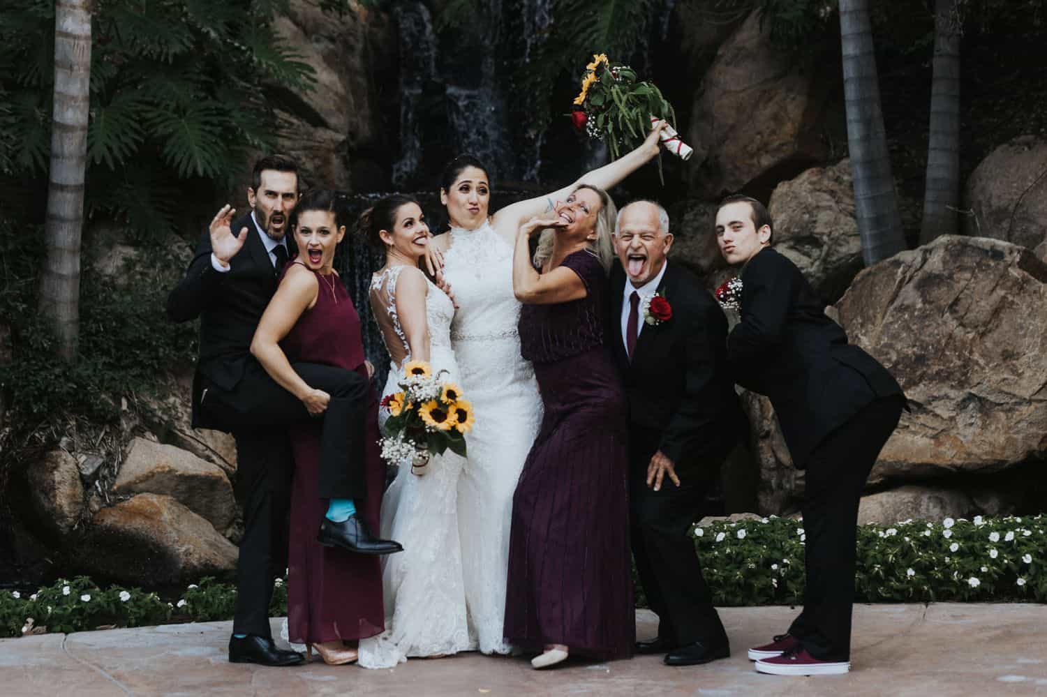 A family strikes a silly pose during their wedding day portrait