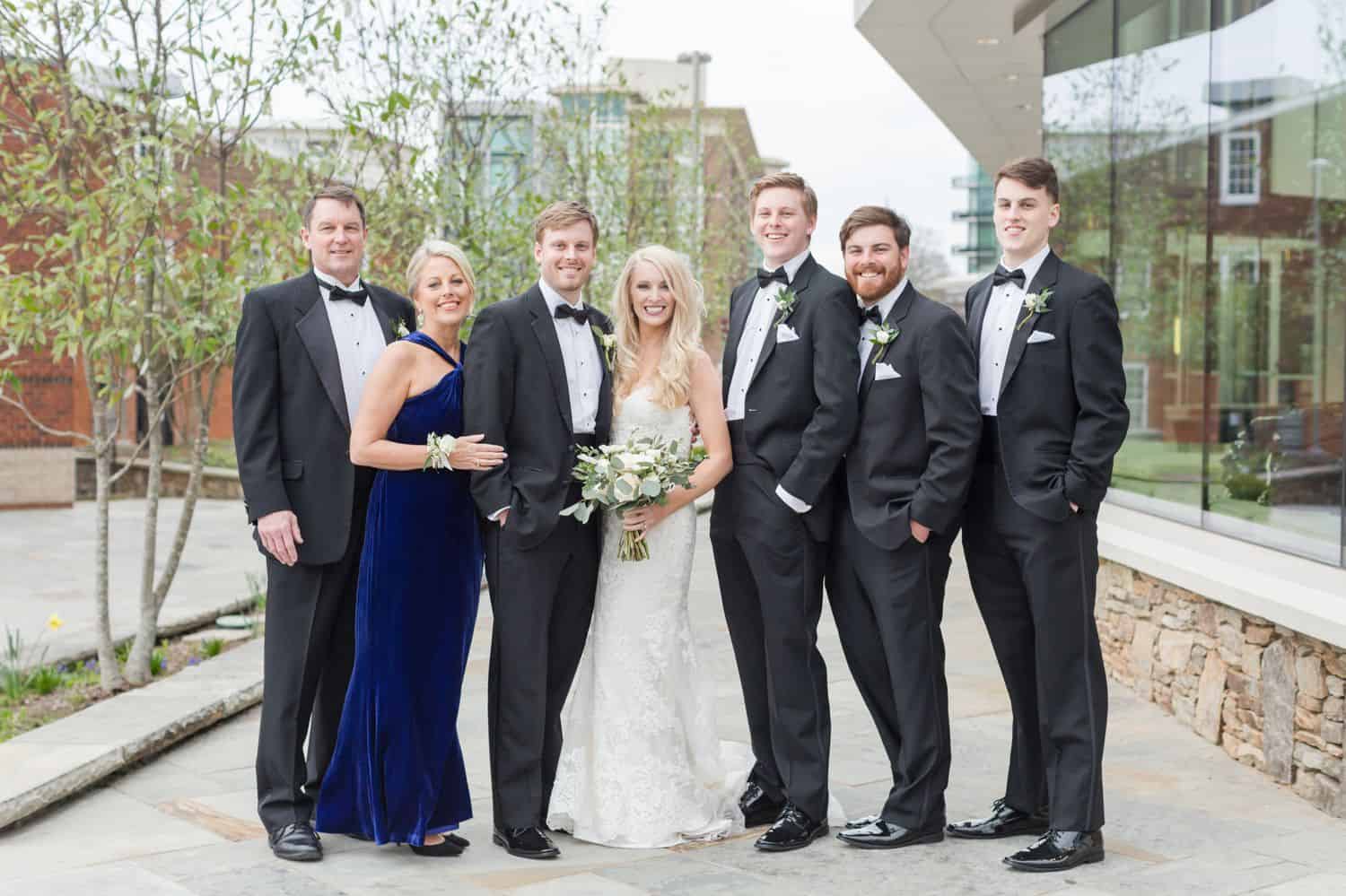 A bride and groom pose with family members for a wedding day portrait