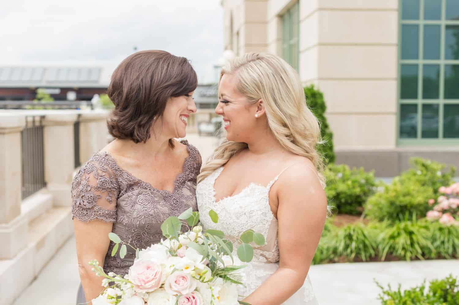 A bride looks at her mother during their wedding day portrait together