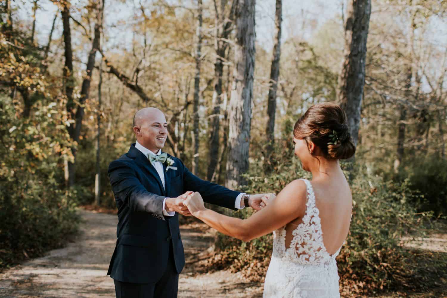 A bride and groom hold hands and gaze at one another during their first look.