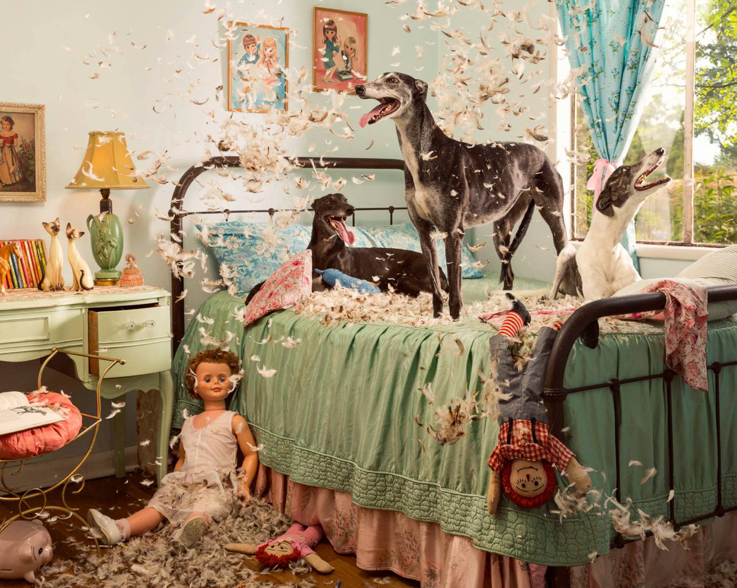 Photo: Holly Andres's photograph of greyhounds playing with feather pillows in a colorfully decorated room fills with trinkets, figurines, and dolls.