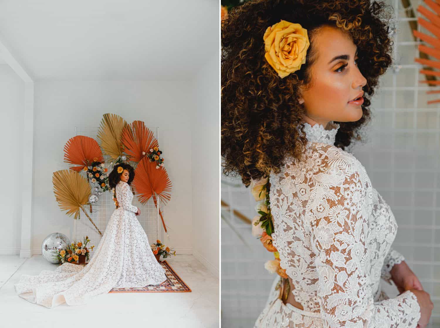 A bride in a high-neck laced gown poses in a white room decorated with yellow and orange flowers.