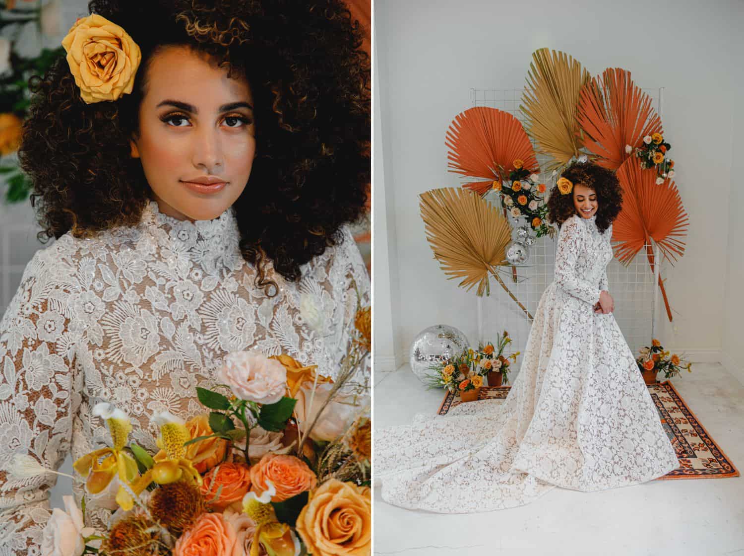 A bride in a high-neck laced gown poses in a white room decorated with yellow and orange flowers.