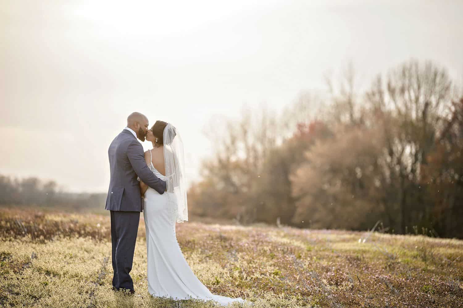 A bride and groom stand on a hill