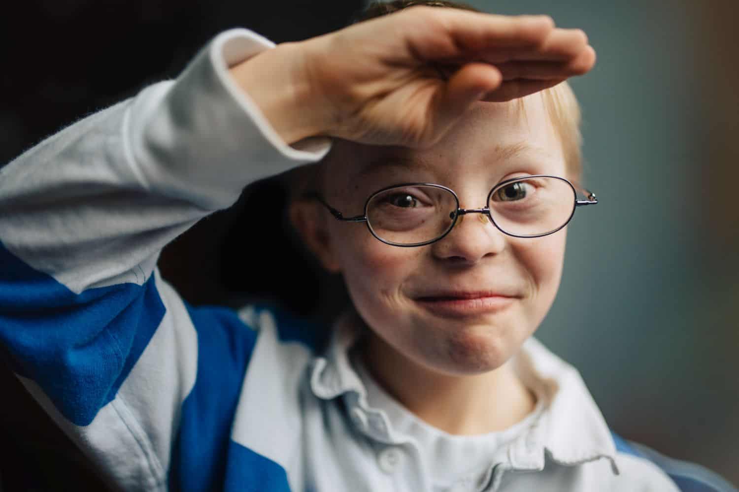 A little boy with Down syndrome grins and salutes Kate T. Parker's camera. Photographed for The Heart of a Boy