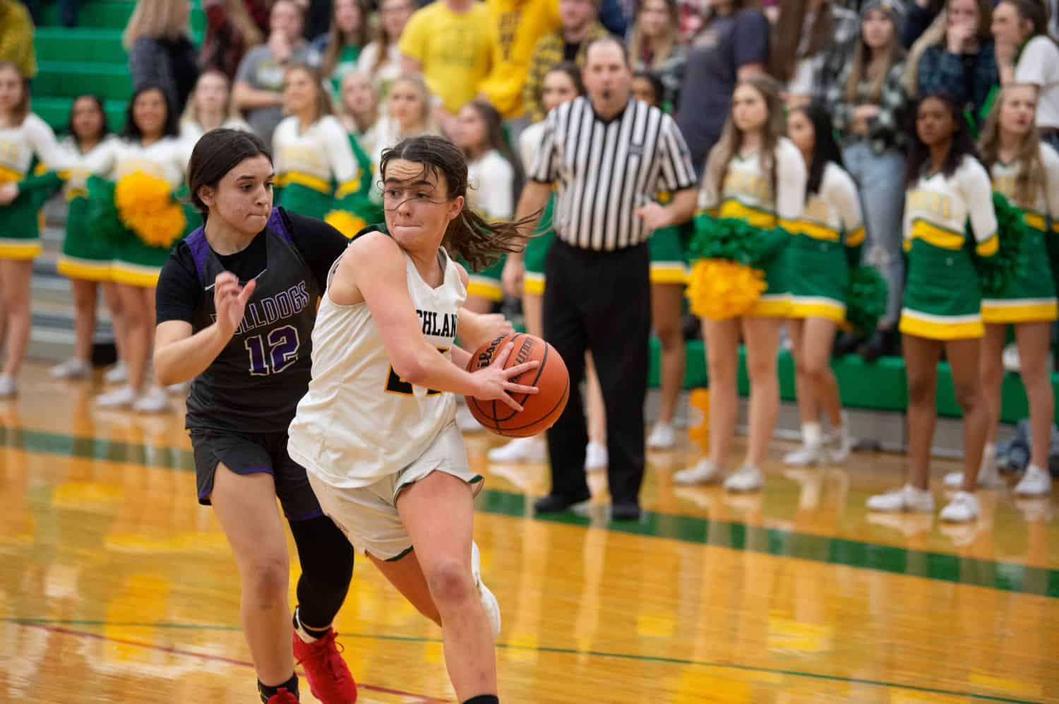 Two high school girls battle for the basketball during a game