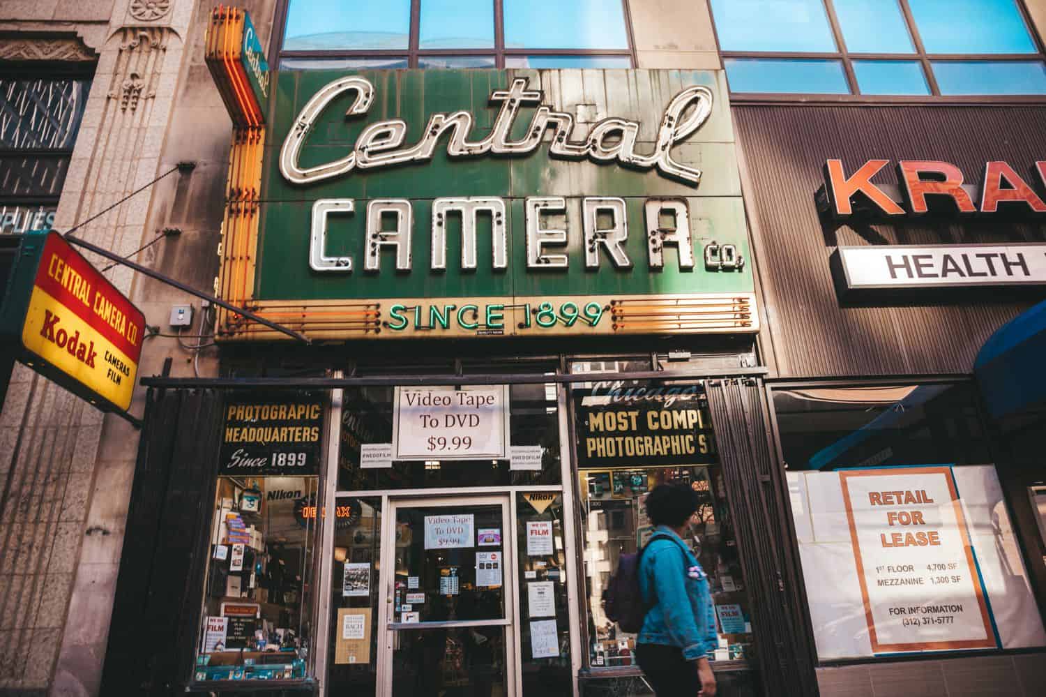 The Central Camera storefront is photographed with a person in a blue hoodie walking past.