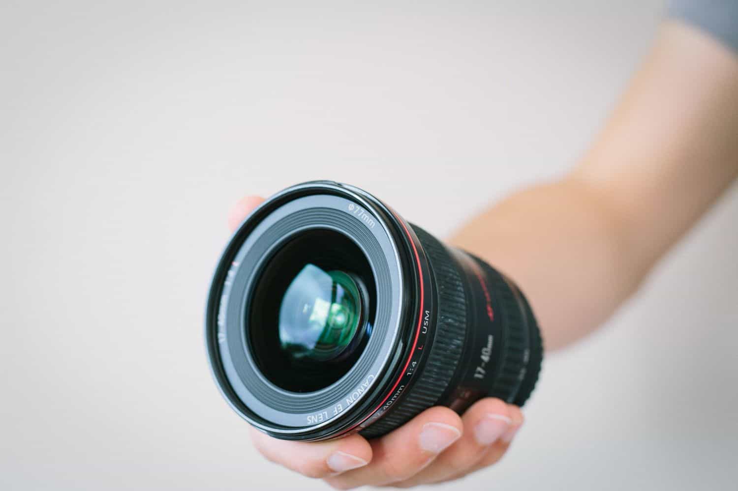 Someone holds a wide angle lens in front of a white wall.