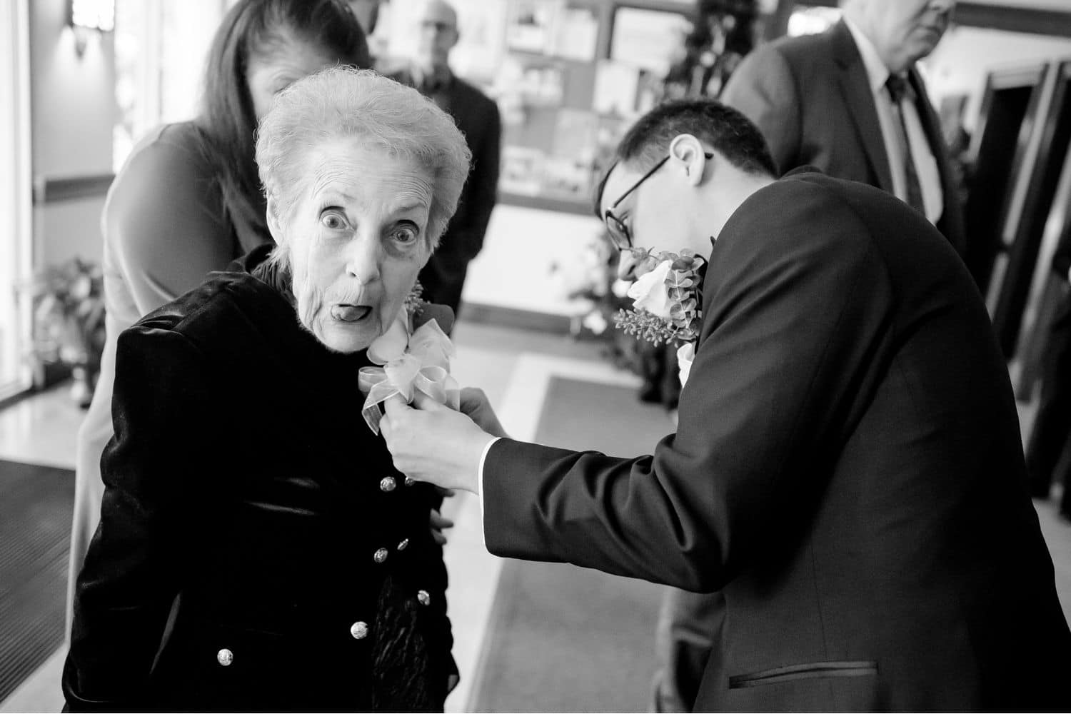 Make Money with Photography: Groom pins a boutonniere on his grandmother as she makes a silly face