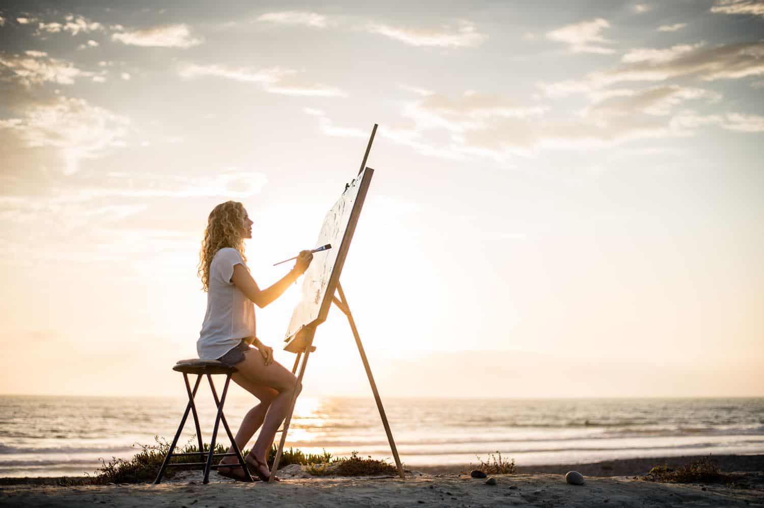 Silhouette of woman painting on the beach.