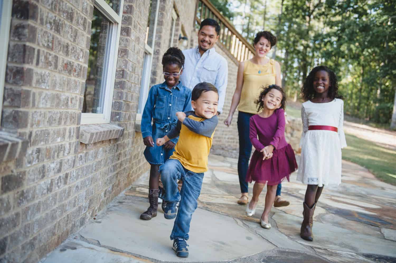 A family walks down a sidewalk wearing brightly colored clothing.
