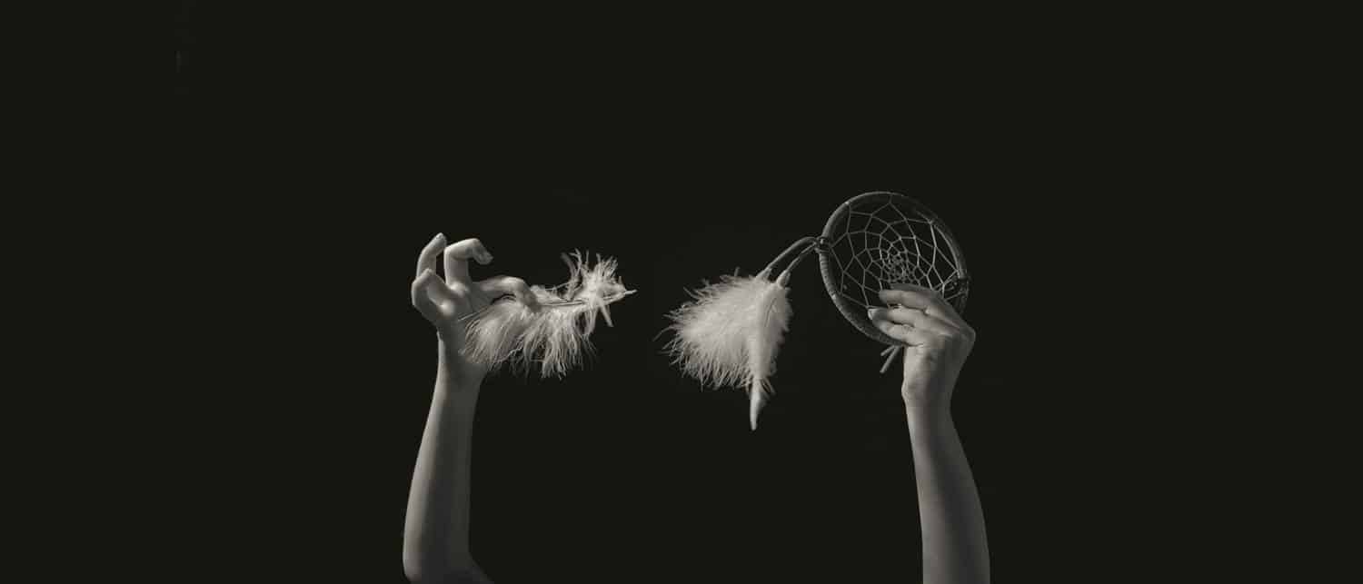 Nolan Streitberger's photograph of his daughter Haley's hands. She holds a feather in one hand and a dreamcatcher in the other.