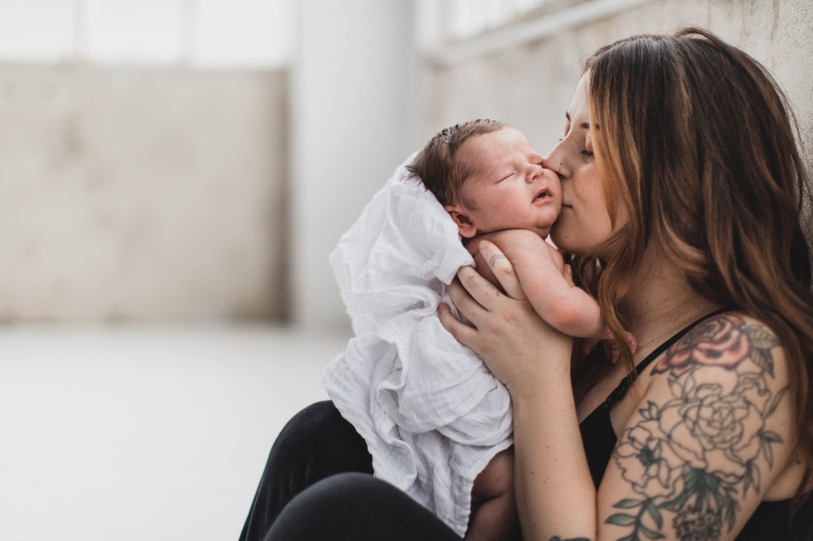 Mom holding and kissing her newborn baby