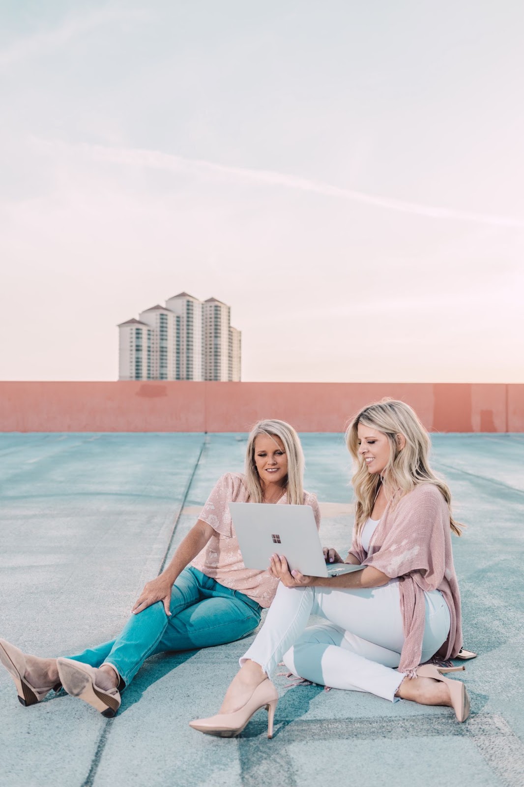 Personal branding photograph of two girls sitting on a rooftop at sunset