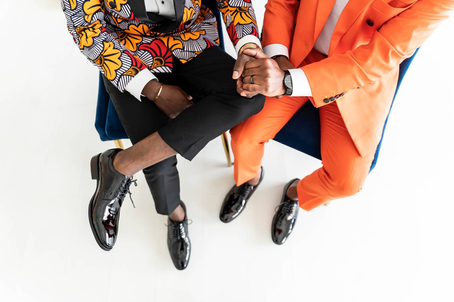 This detail shot highlights the clasped hands of two engaged men