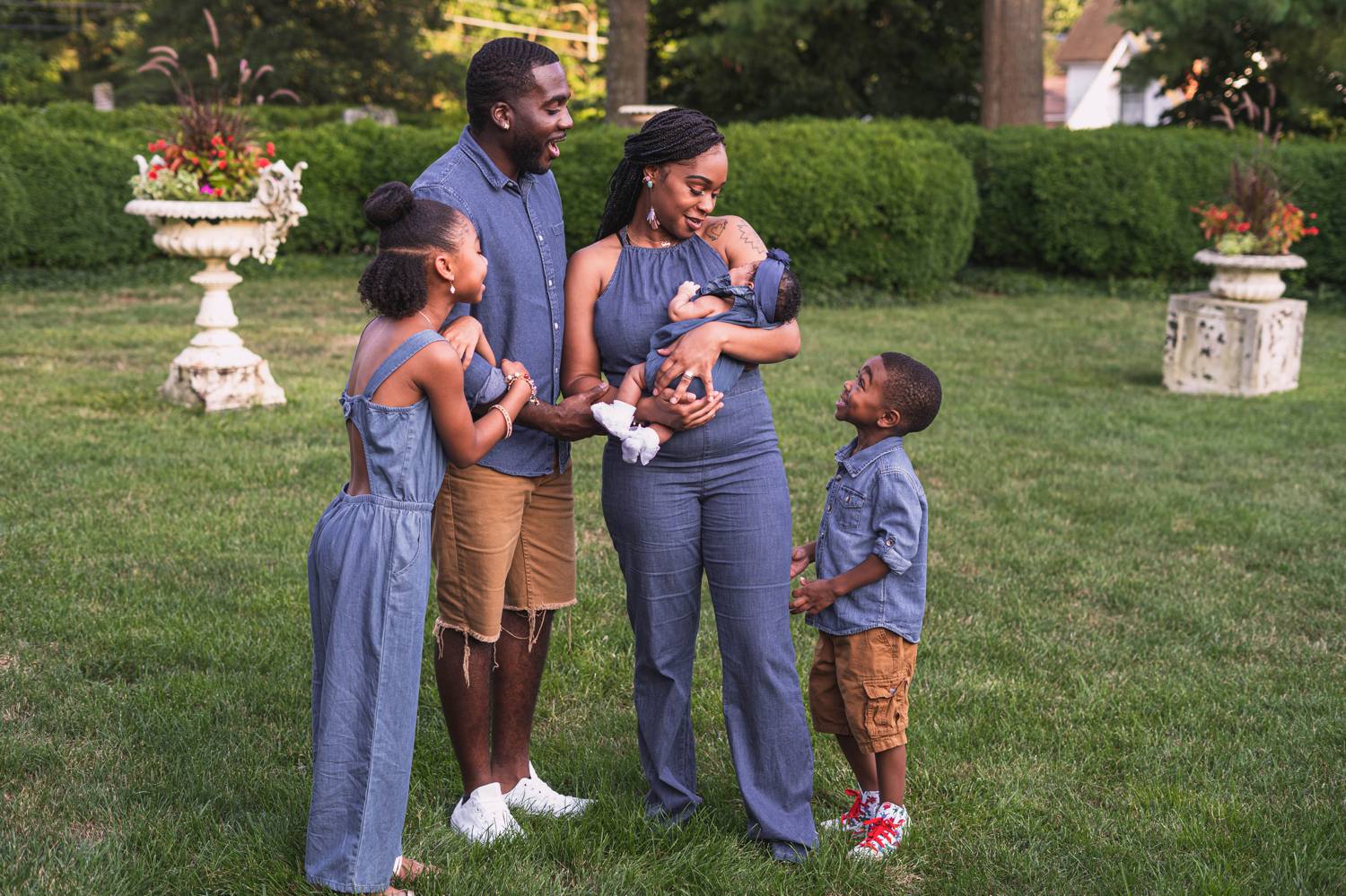 A beautiful Black stands outside in their stunning yard gazing at their newborn baby.