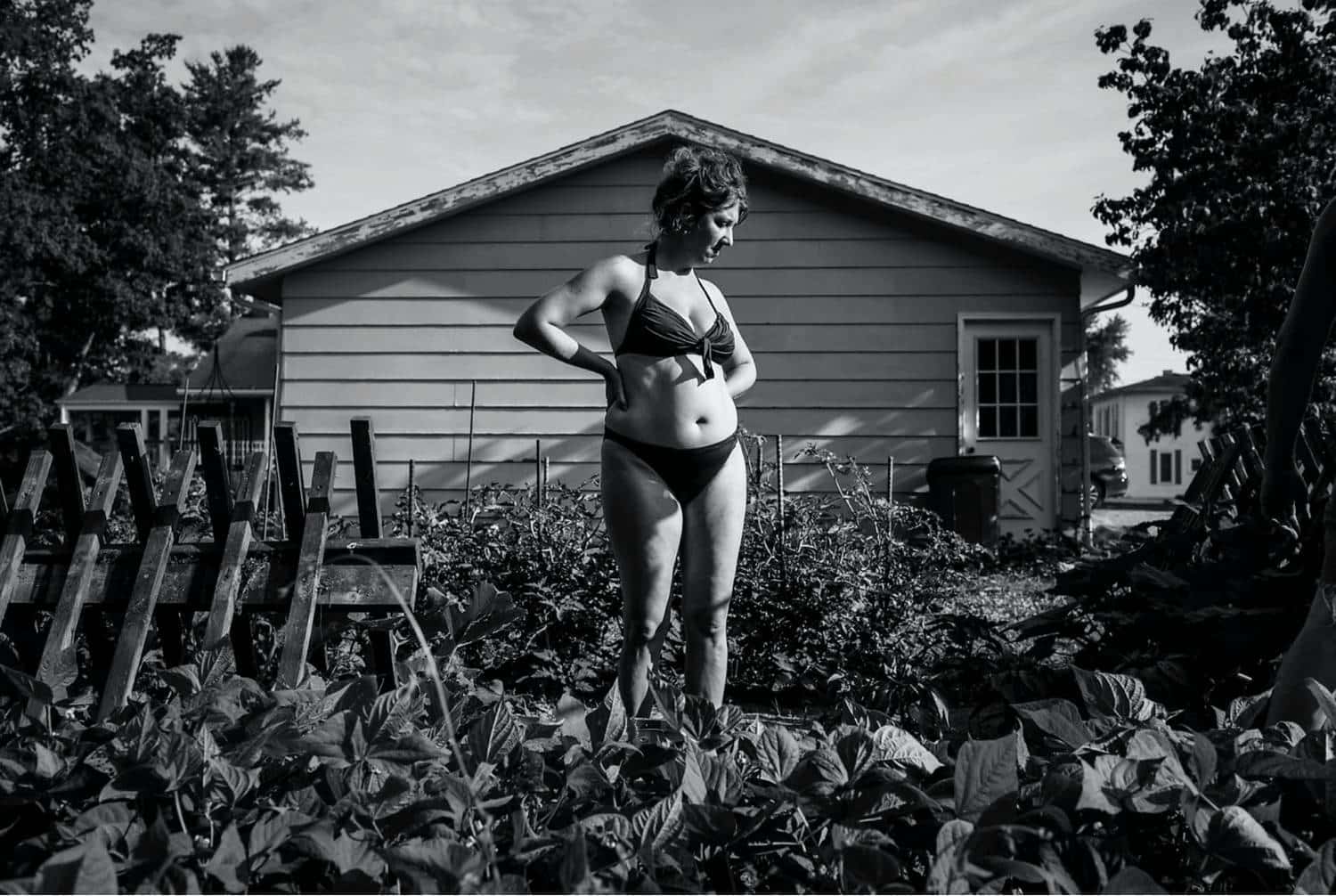 Photo: Rebecca Kiger's black and white photo of a woman in a bikini standing in her brightly sunlit garden.