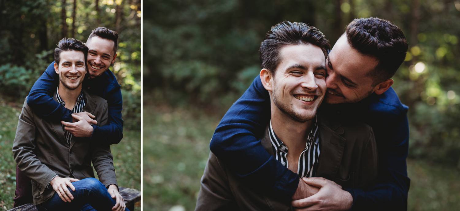 One man sits as his husband wraps his arms around his shoulders from behind