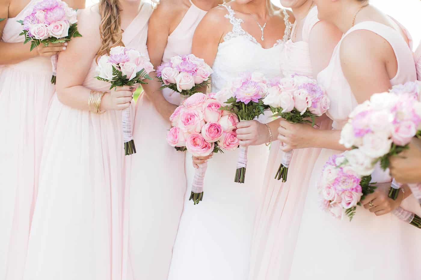 bridesmaids in pink dresses holding pink and purpose rose bouquets by customer service whiz cinnamon wolfe