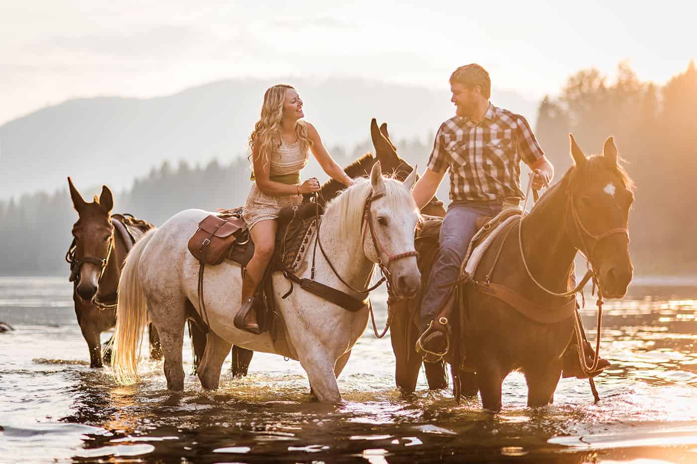 Epic Montana Photo Locations - beautiful couple on horseback in a river at sunset