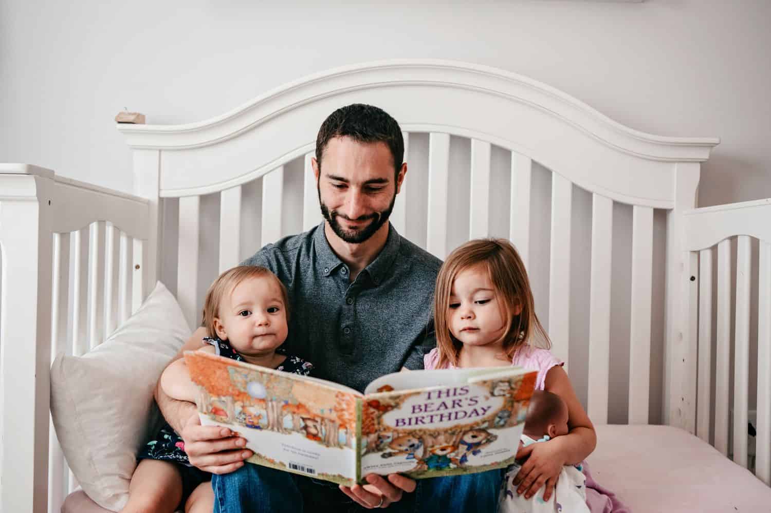 Dad reads a book to his two little daughters.