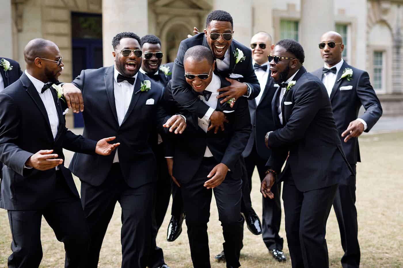 This is the Key to Amazing Client Relationships | A throng of groomsmen in black tuxes horseplay in the courtyard of a beautiful hotel.