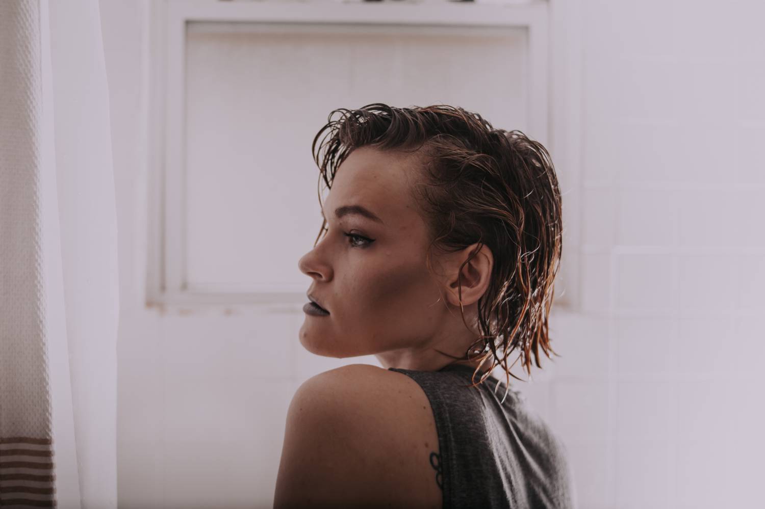 A woman sits in profile in a bathtub wearing a gray bodysuit.