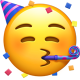 A yellow emoji face wearing a blue and pink striped party hat and blowing a blue party horn, surrounded by colorful confetti. The emoji has closed eyes and rosy cheeks, suggesting a celebratory or affectionate mood.