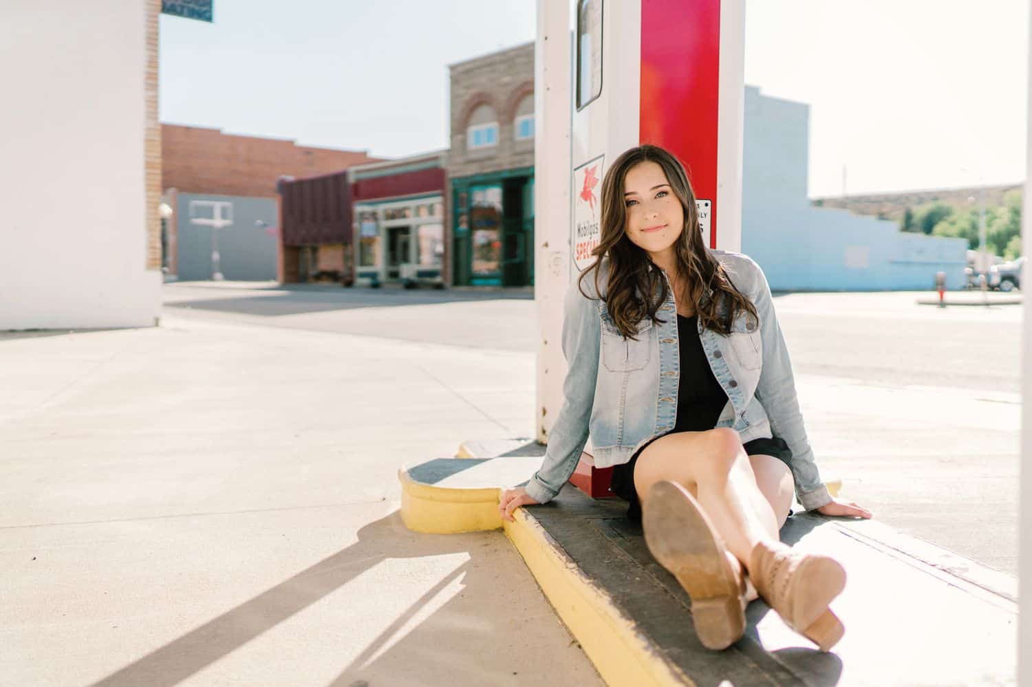 A senior girl leans against the pump in front of an old gas station