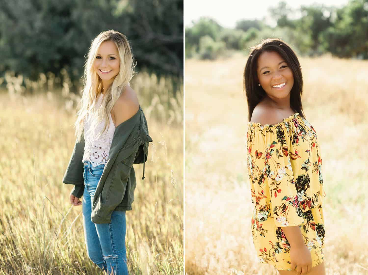 Two senior girls stand casually in a brightly lit field