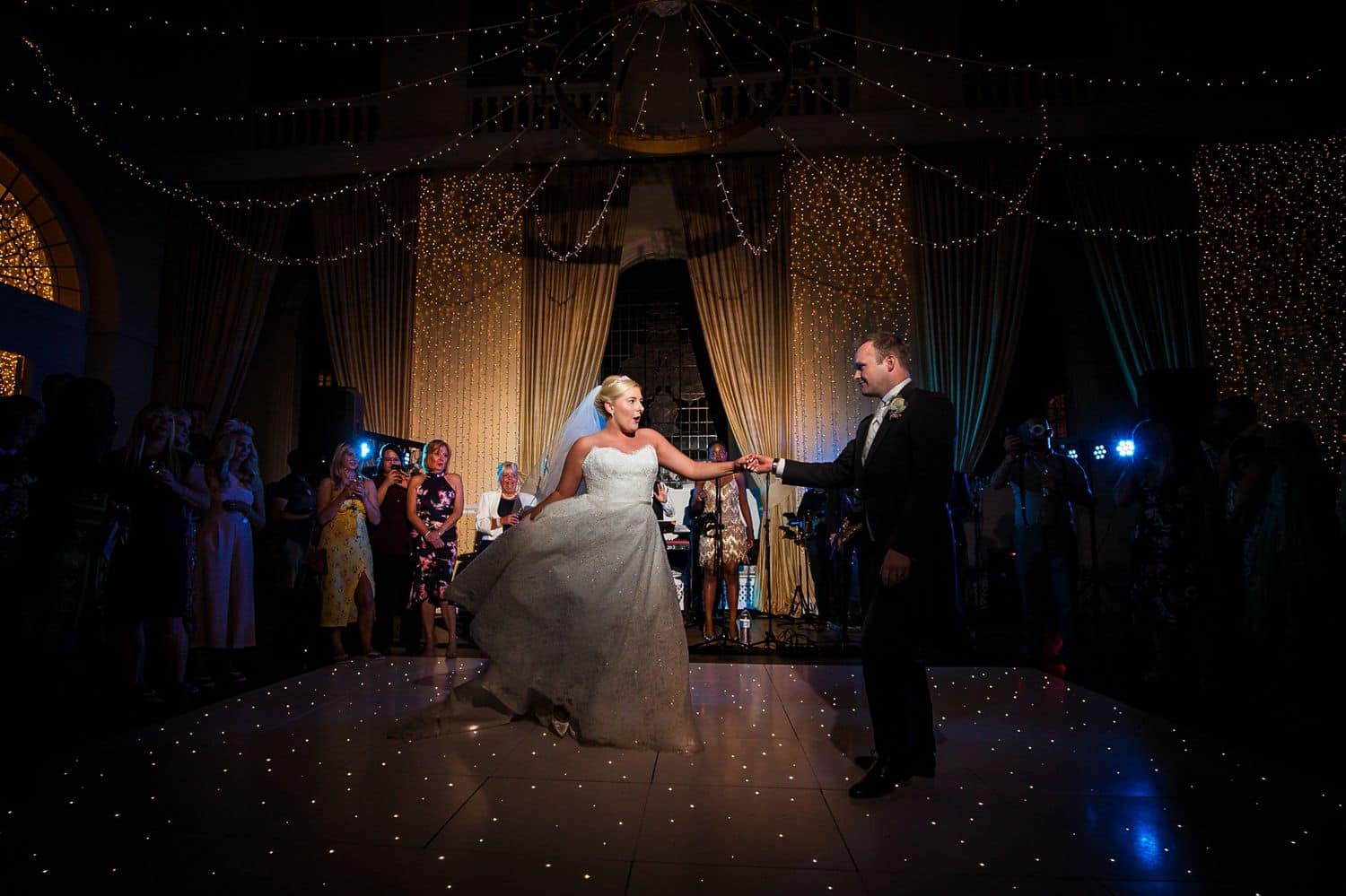 A bride and groom dance elegantly on a ballroom dance floor