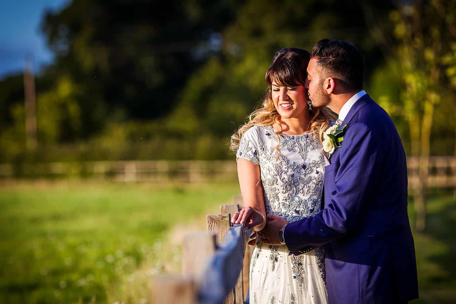 A bride and groom hold each other close while standing in the sun for their first look