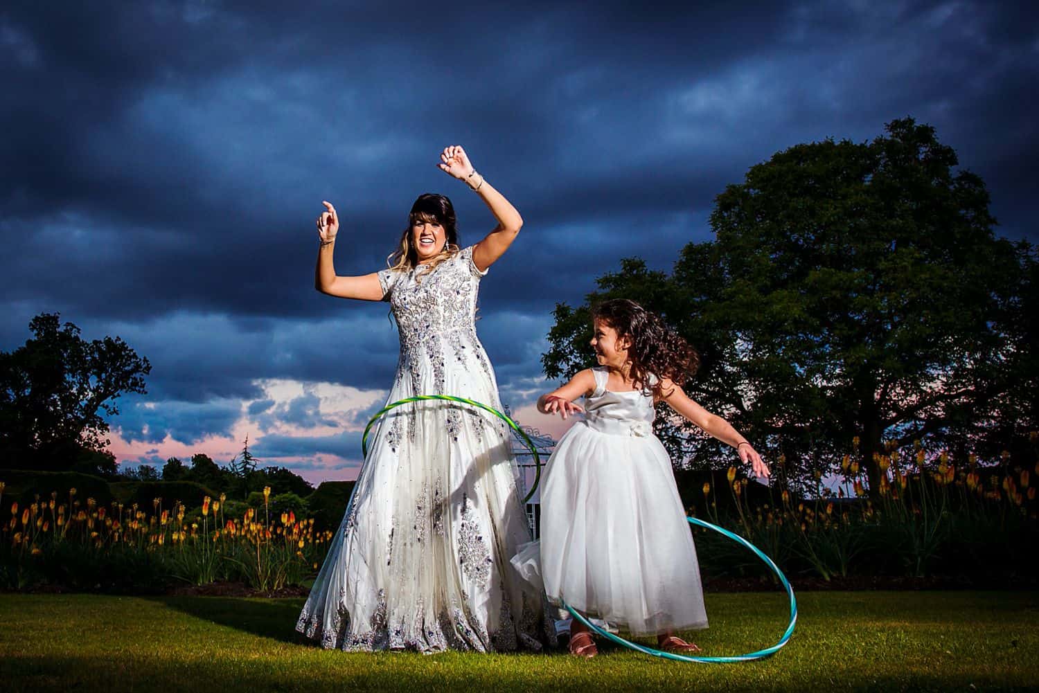 A bride and her flower girl twirl hula hoops at sunset