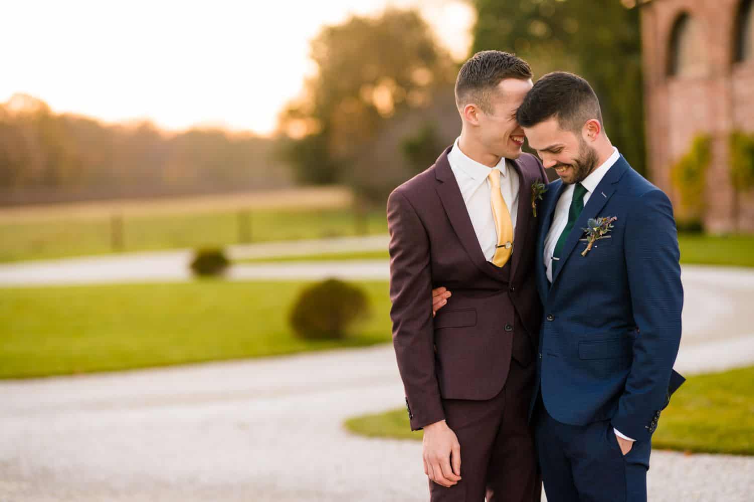Two grooms snuggle close outside on their wedding day