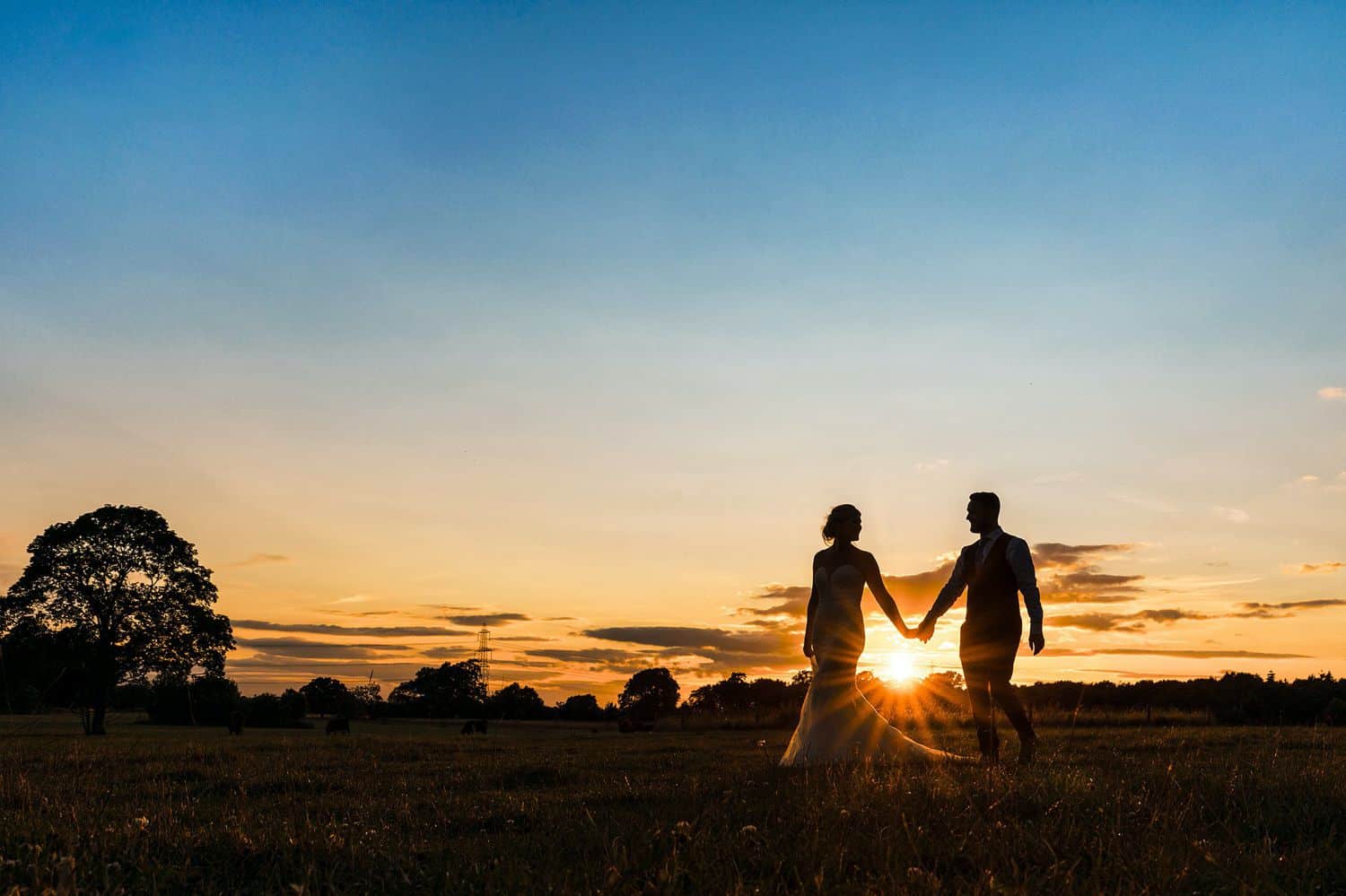 Silhouette of a bride and groom walking along the beach at sunset