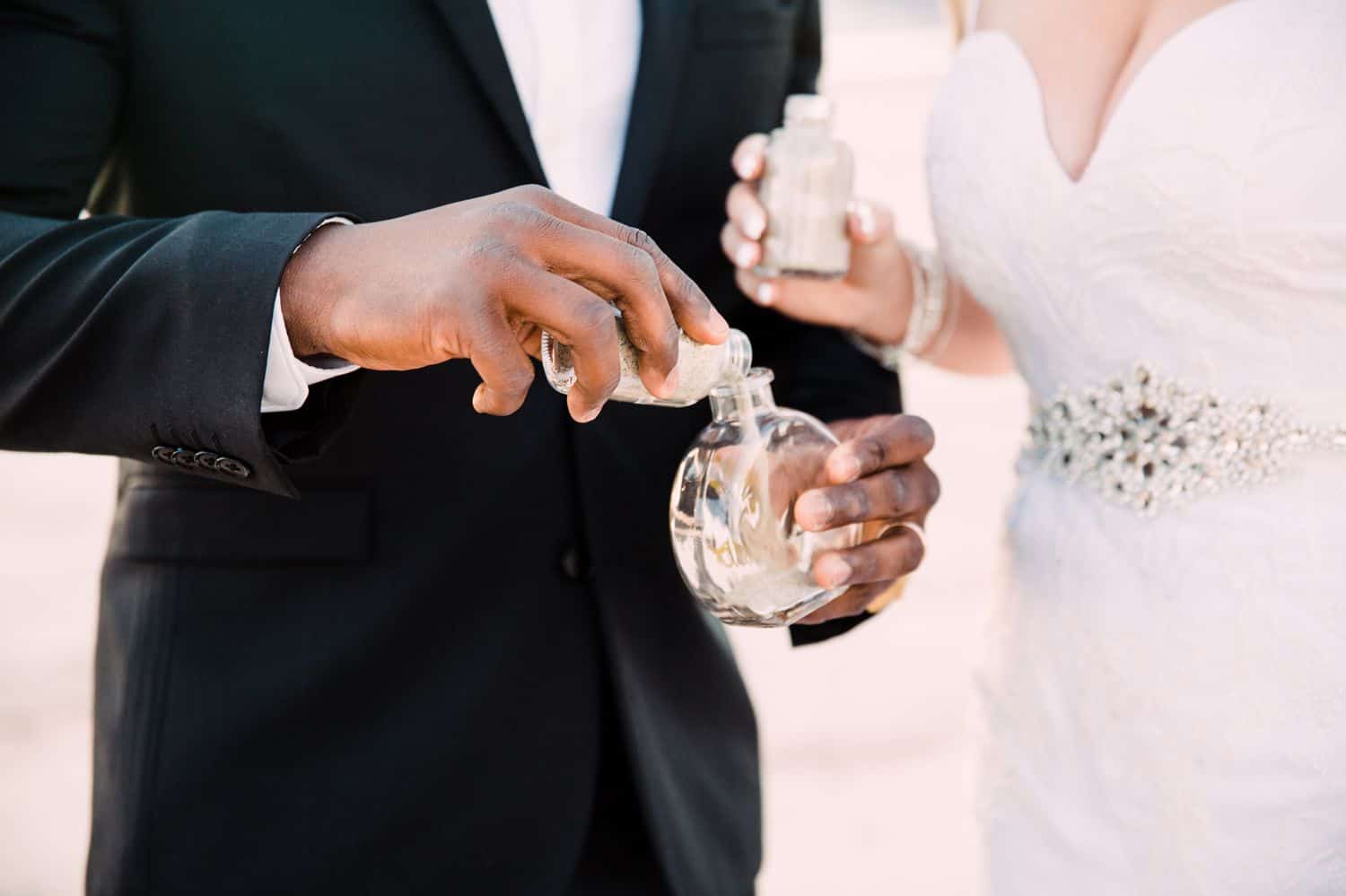 A bride and groom take part in a sand-blending ritual during their desert wedding ceremony