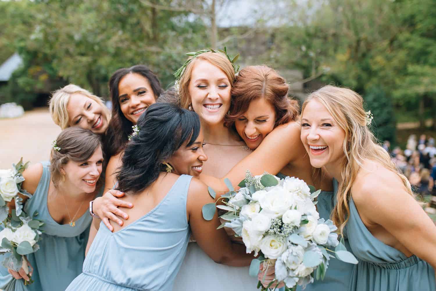 Bridesmaids in pale blue dresses gather around the bride for hugs on the wedding day