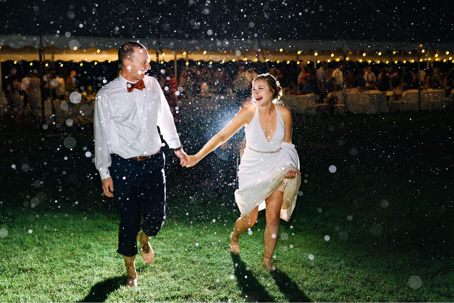 A bride and groom run through the rain at the end of their wedding reception